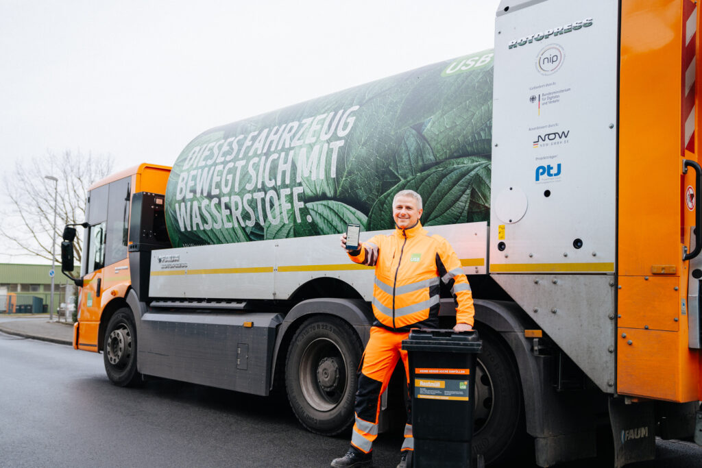 Tanklaster mit einer Person in orangener Arbeitskleidung.