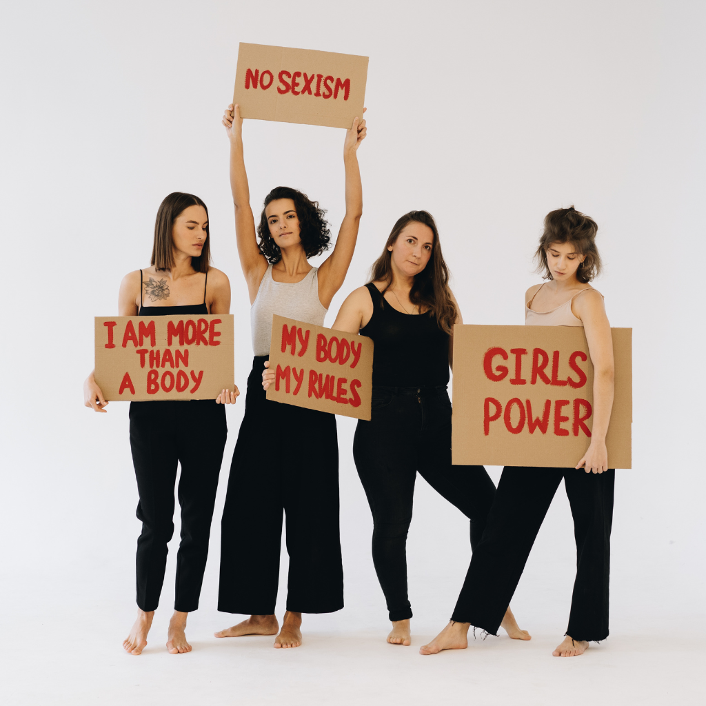 Vier junge Frauen halten Protestschilder zu Gleichberechtigung und Feminismus.